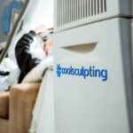 Accent Skin Tightening performed on stomach of Laser & Wellness Center patient as she stands next to CoolSculpting machinery.