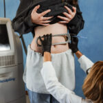 Accent Skin Tightening performed on stomach of Laser & Wellness Center patient as she stands next to CoolSculpting machinery.